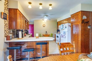 Una cocina con armarios de madera, encimera blanca y una barra con taburetes.