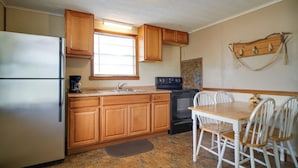A kitchen with wooden cabinets, a refrigerator, a stove, and a dining table with chairs. - Lakefront Cabin in Dandridge w/ Fire Pit & Grill! (Dandridge)