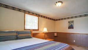 A neatly made bed with striped pillows, a bedside lamp, and a 'Welcome to the Lodge' sign on the wall. - Lakefront Cabin in Dandridge w/ Fire Pit & Grill! (Dandridge)