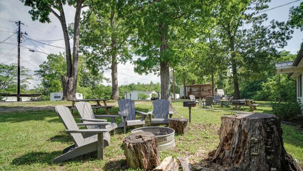 An outdoor seating area with Adirondack chairs, a fire pit, and a wooden deck. - Lakefront Cabin in Dandridge w/ Fire Pit & Grill! (Dandridge)