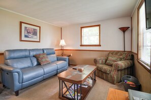 A living room with a blue sofa, plaid armchair, and a coffee table with magazines. - Lakefront Cabin in Dandridge w/ Fire Pit & Grill! (Dandridge)