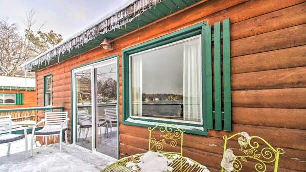 Una cabaña de madera con puerta y ventanas de vidrio, mobiliario exterior y un patio cubierto.