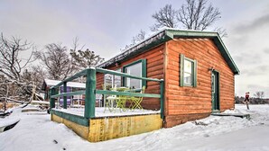 Una cabaña de madera con puerta y ventanas verdes, rodeada de nieve.