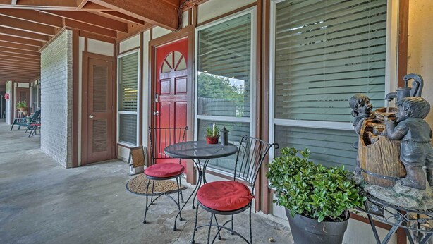 A covered outdoor area with a red door, a table with chairs, and a statue of a figure playing a flute. - 5 Mi to Dtwn: Austin Gem w/ Pool, Pets Welcome (Austin)