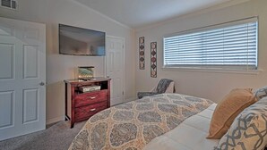 A bedroom with a bed, a dresser, a chair, a window with blinds, and a wall-mounted TV. - 5 Mi to Dtwn: Austin Gem w/ Pool, Pets Welcome (Austin)