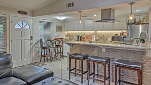 A modern kitchen with a central island, bar stools, and a dining area with a chandelier. - 5 Mi to Dtwn: Austin Gem w/ Pool, Pets Welcome (Austin)