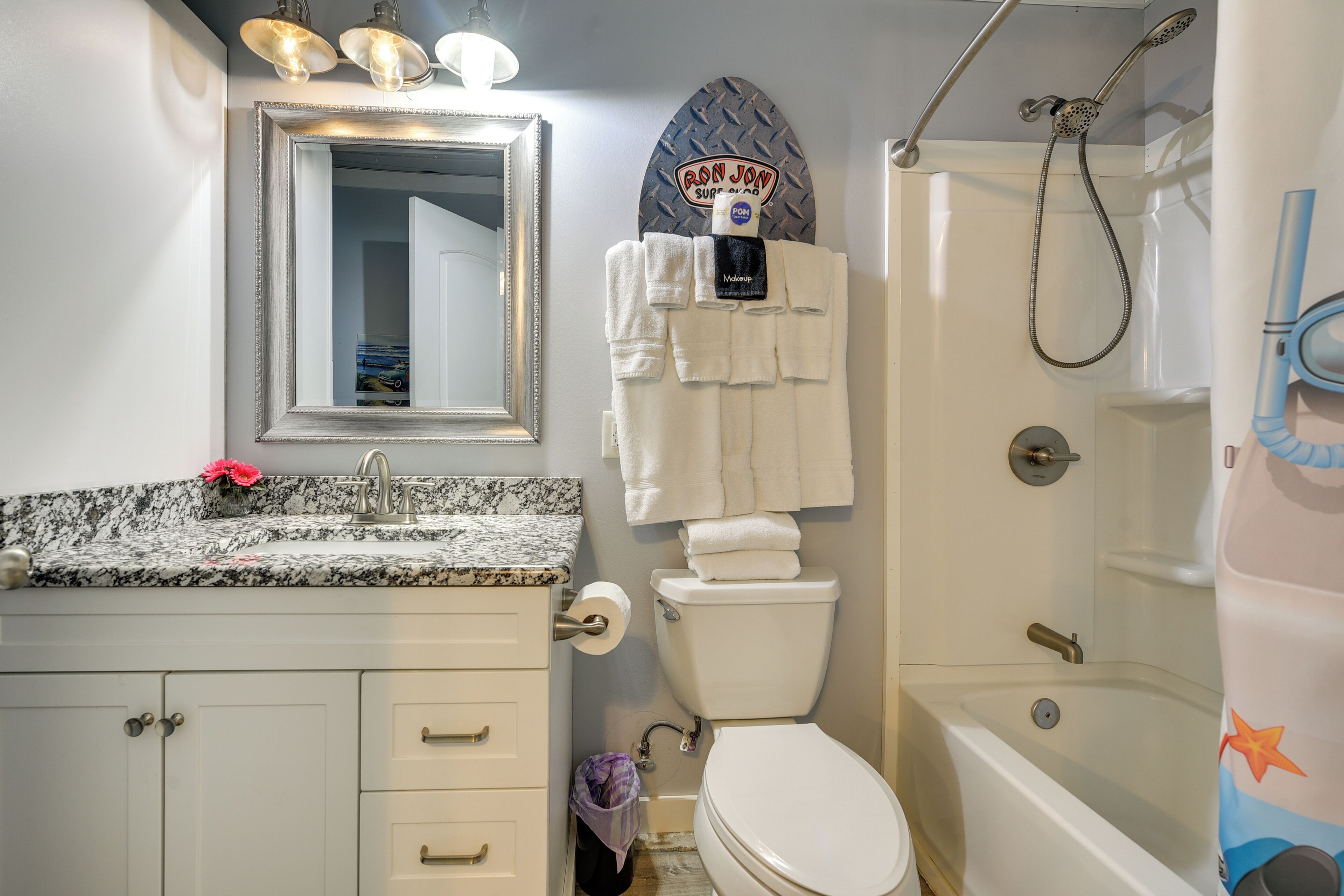 A bathroom with a sink, mirror, toilet, and shower.