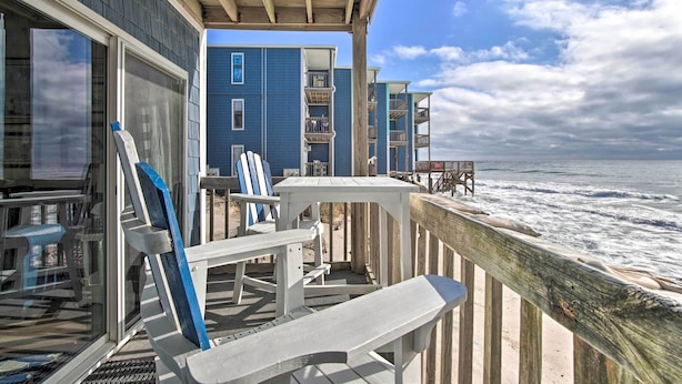 A wooden deck with white chairs and a table overlooking the ocean. - Oceanfront Condo w/ Views in North Topsail Beach! (Sneads Ferry)