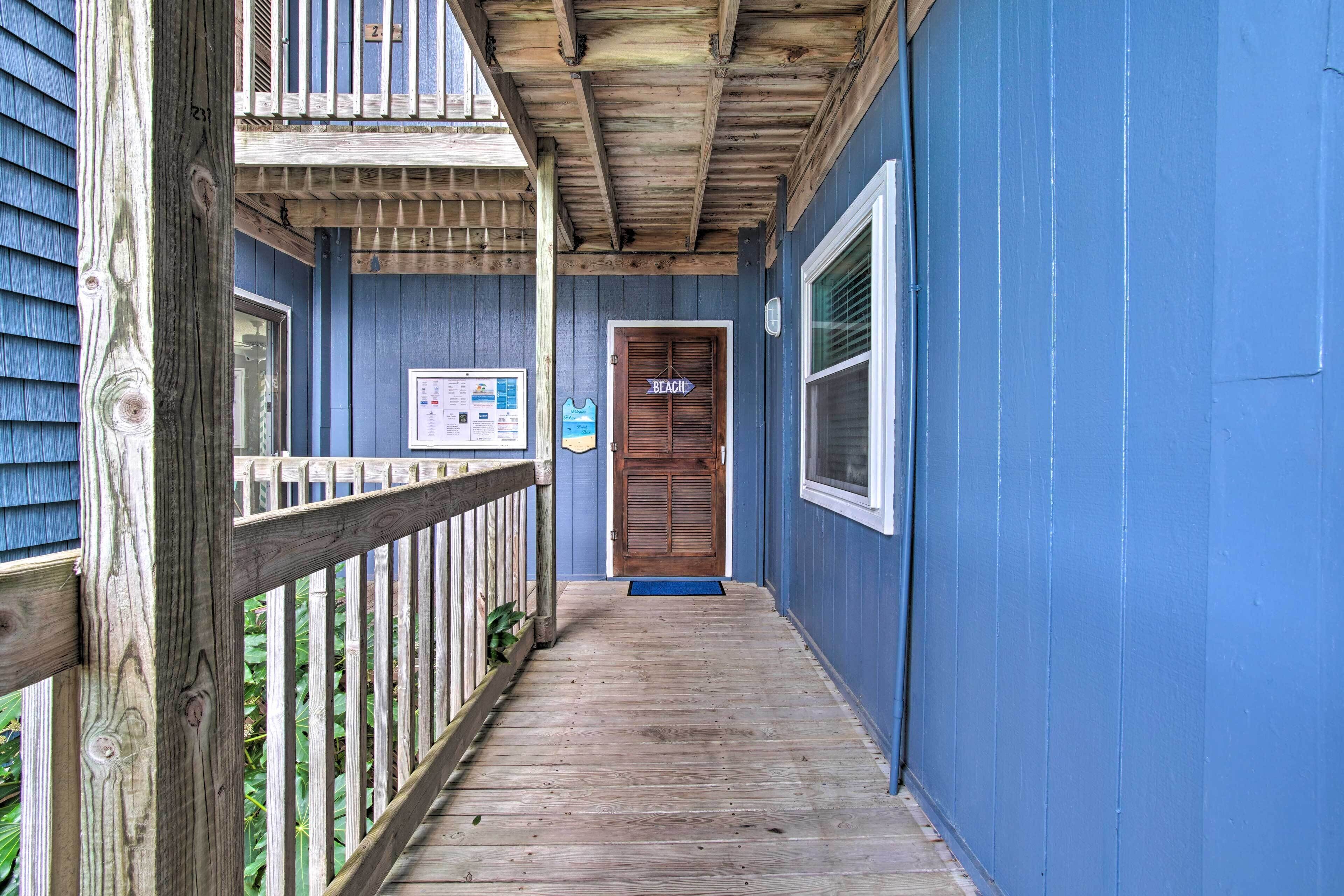 A wooden deck leading to a door labeled "BEACH" with a blue exterior wall.