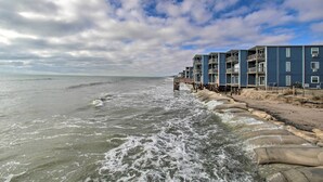 A beachfront hotel with multiple-story buildings, a sandy beach, and waves crashing onto the shore. - Oceanfront Condo w/ Views in North Topsail Beach! (Sneads Ferry)