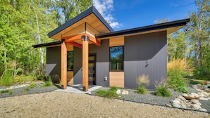 A modern house with a wooden porch, large windows, and a gravel driveway. - Rock Creek Retreat: Creekside Cabin Near Red Lodge (Red Lodge)