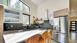 A modern kitchen with a large island, stainless steel appliances, and wooden chairs. - Rock Creek Retreat: Creekside Cabin Near Red Lodge (Red Lodge)