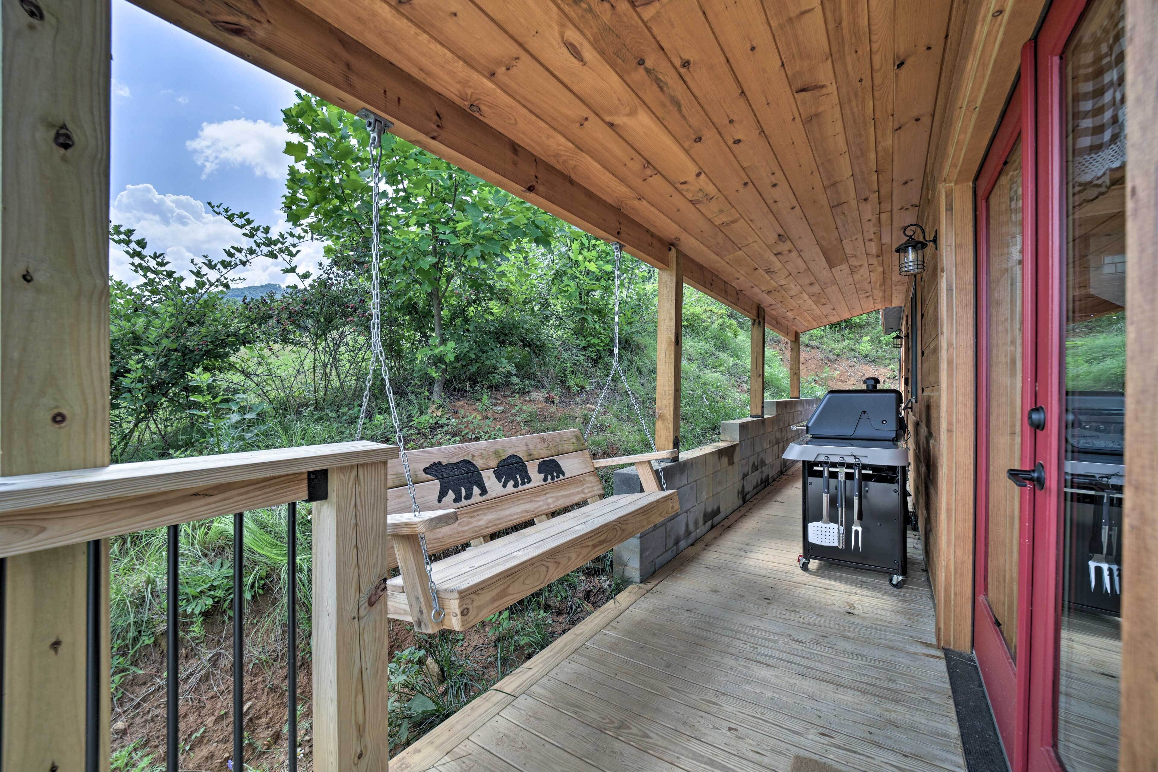 Une terrasse en bois avec un banc, un barbecue et une porte rouge.