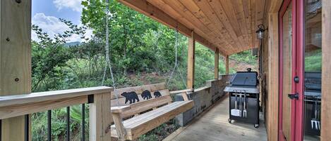 Une terrasse en bois avec un banc, un barbecue et une porte rouge.