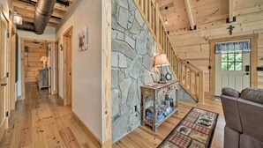 A wooden interior with a stone wall, a staircase, and a sofa. - Luxe Log Cabin w/ Modern Finishes & Mtn Views (Maggie Valley)