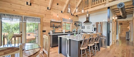 Una cocina amplia con armarios de madera, una isla central y un comedor con sillas de madera.