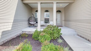 A covered porch with a seating area, stone steps, and a garden with various plants. - Near Bethany Beach: Resort-style Home w/ Views (Ocean View)