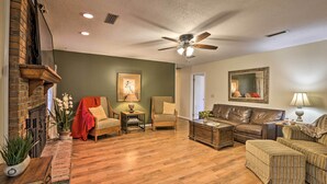 A living room with a brick fireplace, a ceiling fan, a sofa, a chair, and a coffee table. - Quiet Dothan House With Fenced Yard + Fire Pit! (Dothan)