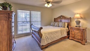 A bedroom with a wooden bed, a nightstand, a dresser, and a ceiling fan. - Quiet Dothan House With Fenced Yard + Fire Pit! (Dothan)