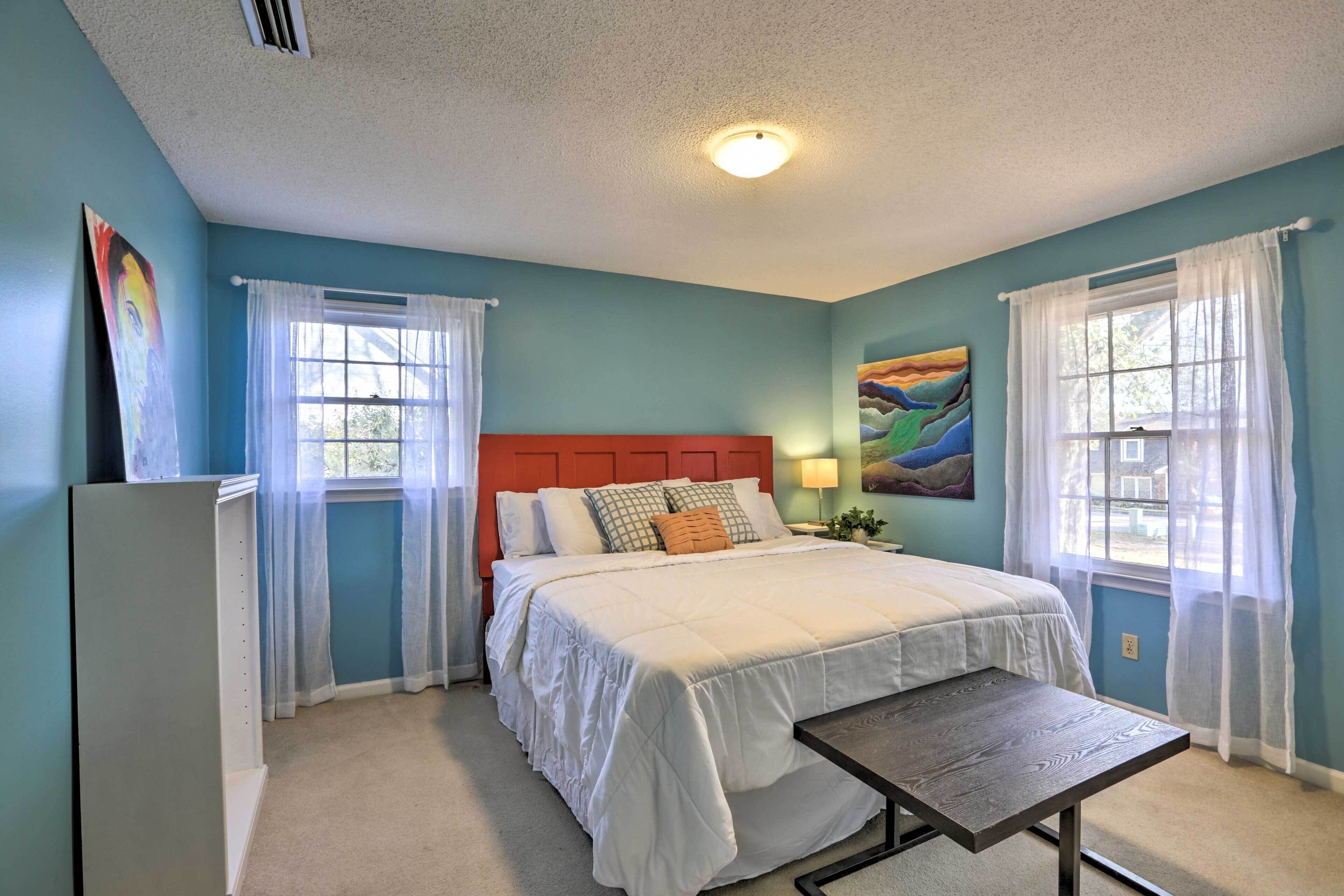 A bedroom with a bed, a nightstand, a lamp, and a window with curtains.