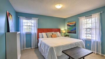 A bedroom with a bed, a nightstand, a lamp, and a window with curtains.