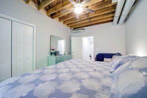 Une chambre à coucher avec un lit, une commode, un miroir et un ventilateur de plafond.