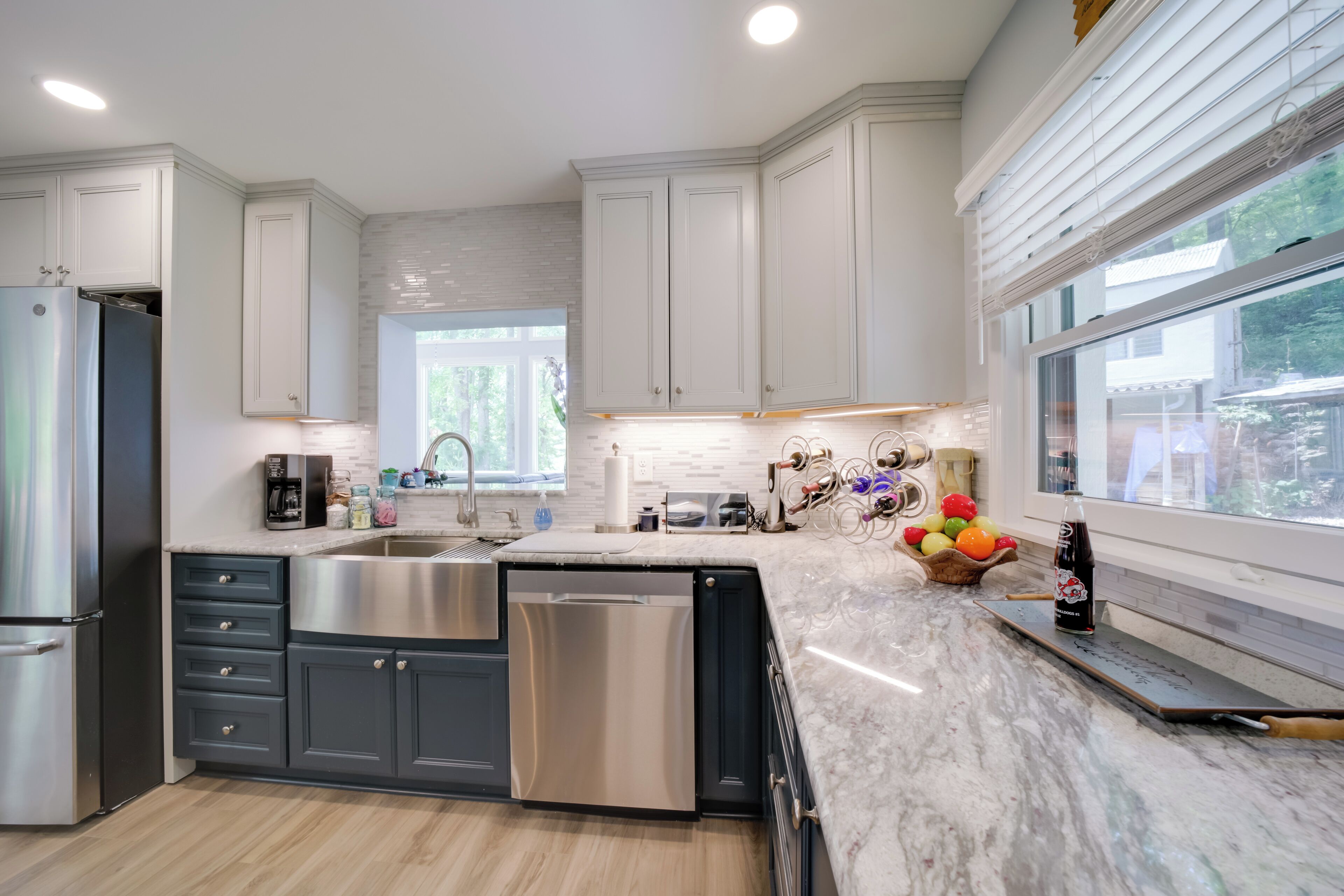 A modern kitchen with white cabinetry, stainless steel appliances, and a marble countertop.