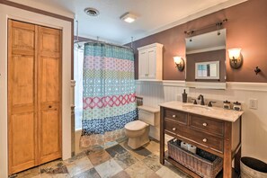 A bathroom with a shower curtain, toilet, vanity, and a mirror. - Peaceful Ranch-style Camano Home on 5 Acres! (Camano Island)