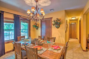 A dining room with a wooden table set for four, surrounded by chairs, with a chandelier above. - Pet-friendly Kingston Home w/ Boat Ramp Access! (Kingston)