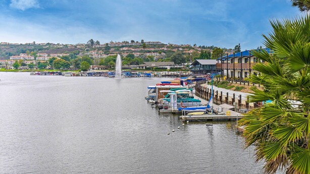 A marina with boats docked, a fountain, and a building with a blue roof. - San Marcos Home w/ Patio & Grill - Walk to Lake! (San Marcos)