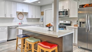 A modern kitchen with white cabinets, a central island with stools, stainless steel appliances, and a skylight. - San Marcos Home w/ Patio & Grill - Walk to Lake! (San Marcos)