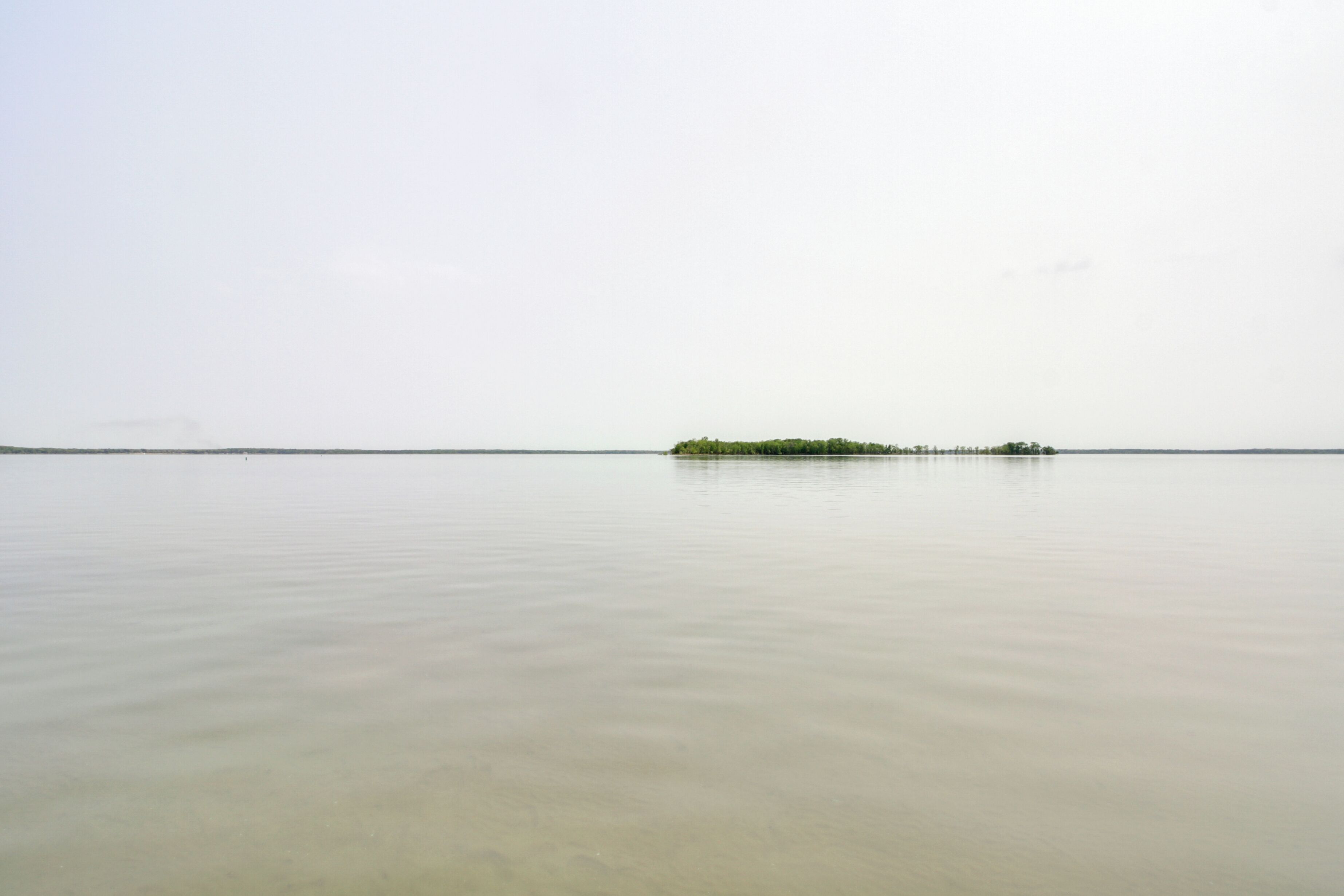 Ein ruhiges Gewässer mit einer kleinen Insel in der Ferne.