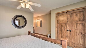 A bedroom with a bed, a ceiling fan, a round mirror, and a wooden wardrobe. - Pelican Lake Retreat w/ Fire Pit, Dock & Grill! (Pequot Lakes)