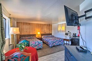 Hotelkamer met twee bedden, een aan de muur bevestigde televisie, een bureau met een computer en een kitchenette.