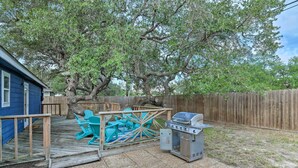 A backyard with a wooden deck, a barbecue grill, and outdoor furniture.