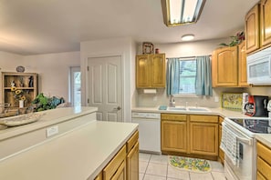 Cocina compacta con armarios de madera, lavavajillas, microondas y estufa.