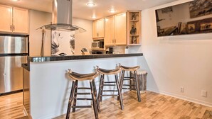 A modern kitchen with wooden cabinets, stainless steel appliances, and a central island with bar stools. - Skier's Dream: Upscale Condo By Teton Village! (Wilson)