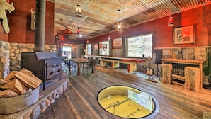 Un interior rústico con chimenea de piedra, muebles de madera y un tragaluz circular.