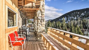 A wooden deck with red chairs and a table, overlooking a forested mountain area. - 'sasquatch Inn' Retreat Near Fishing & Hunting! (Wise River)