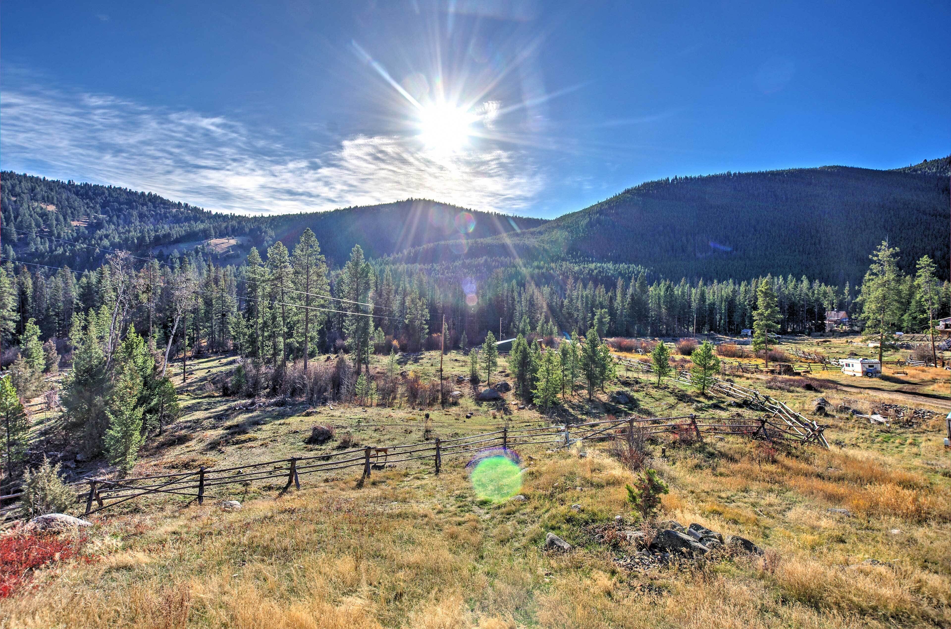 A mountainous landscape with a clear sky, a fence, and a small building.