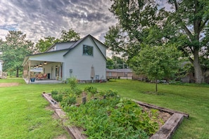 A house with a covered porch, a well-maintained lawn, and a vegetable garden.
