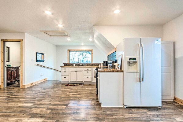 A spacious kitchen with a large island, white cabinetry, and a built-in refrigerator.