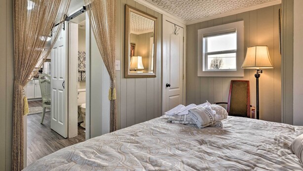 Une chambre à coucher avec un grand lit, une fenêtre, un miroir et une porte donnant sur une salle de bain.
