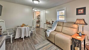 Un salon avec un canapé beige, une table à manger avec des chaises, une lampe et une petite table d’appoint.
