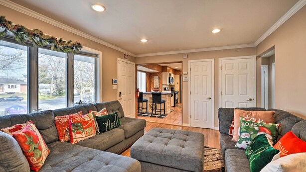 A living room with a gray sectional sofa, ottoman, and a kitchen in the background.