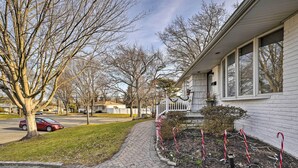 A residential house with a paved driveway, a lawn, and a tree.