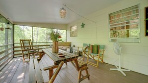 Una terraza de madera con una mesa de comedor, sillas y un ventilador.