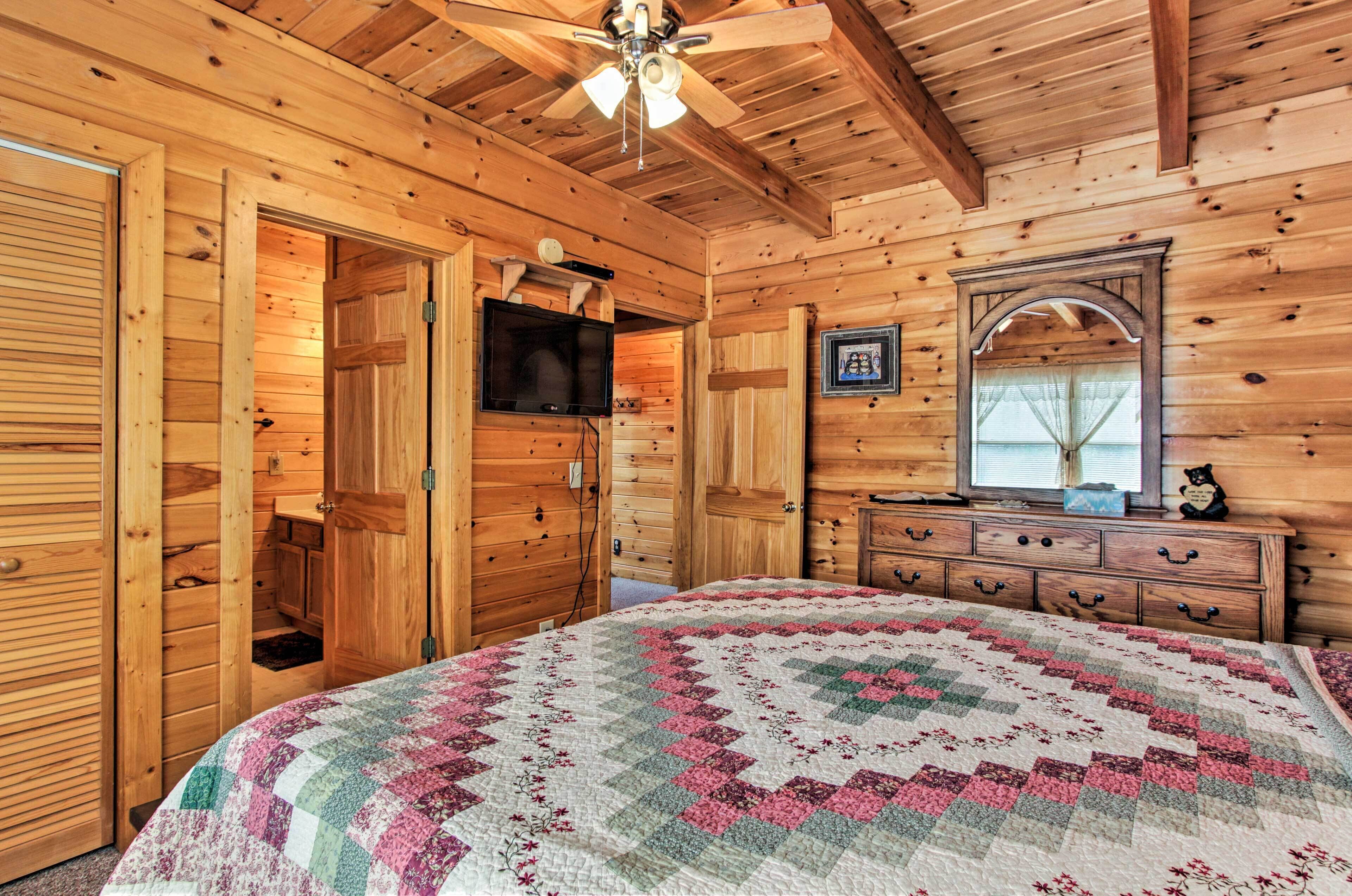 Dormitorio de cabaña de madera con cama, cómoda y ventilador de techo.