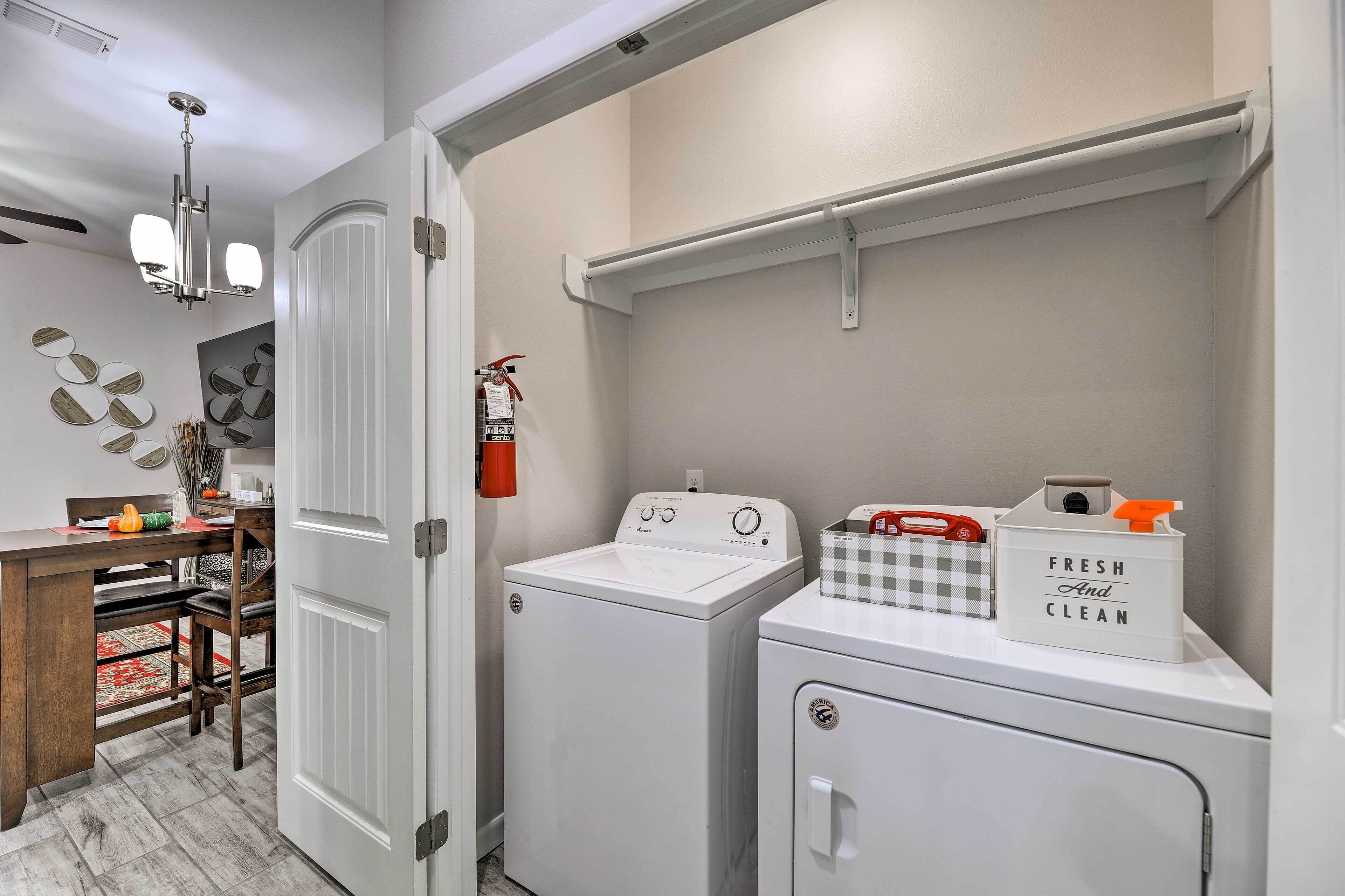A laundry room with a washing machine, dryer, and a shelf with a 'Fresh and Clean' sign.