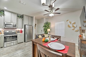 A modern kitchen with stainless steel appliances, a dining area with a wooden table, and decorative wall art. - Quiet Edinburg Apartment: Close to Attractions! (Edinburg)